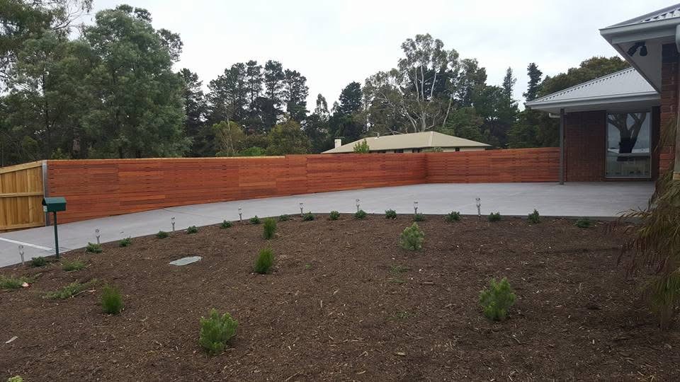 Horizontal hardwood slat fence around a landscaped backyard