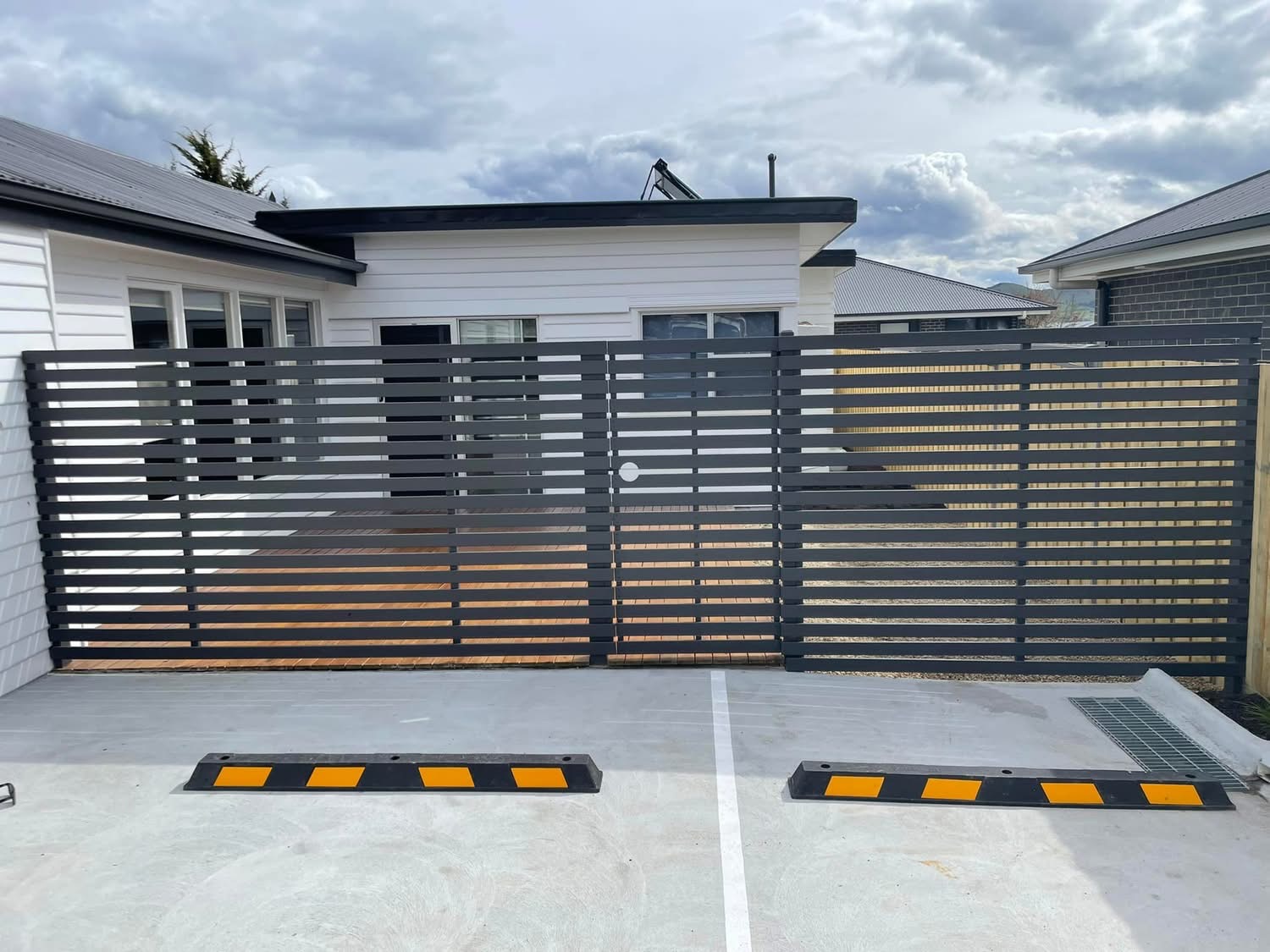 Dark aluminium slat double swing gate on a residential driveway