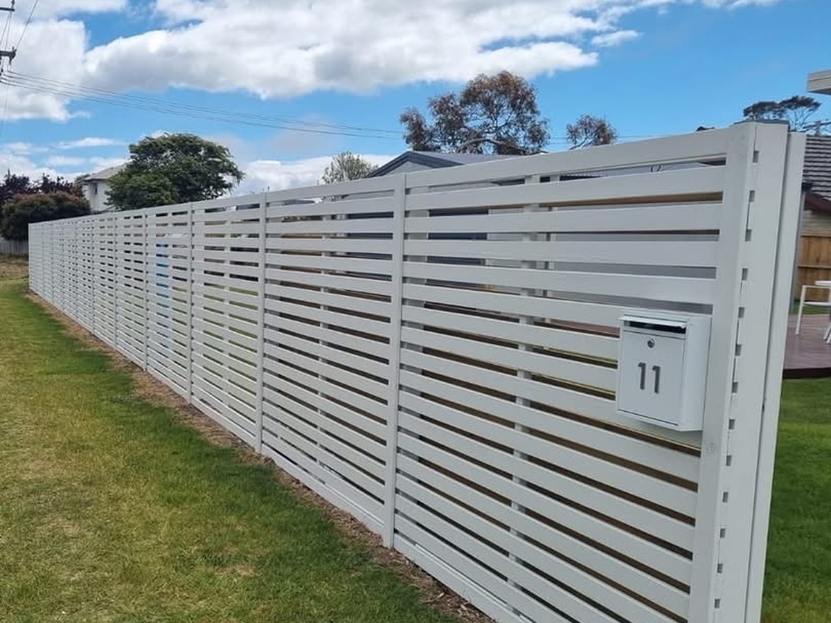 The same treated pine slat fence after painting, finished in white