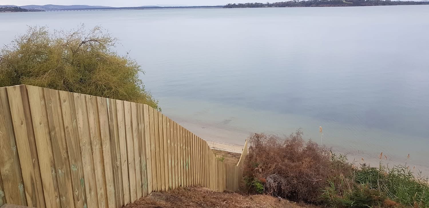 Timber paling fence running down to the water's edge