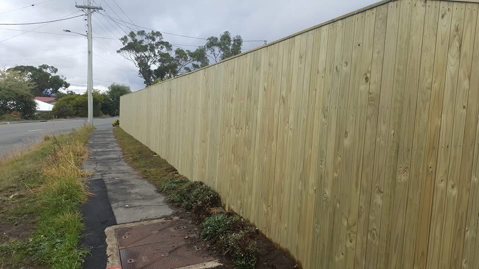 Long timber paling boundary fence beside a suburban footpath